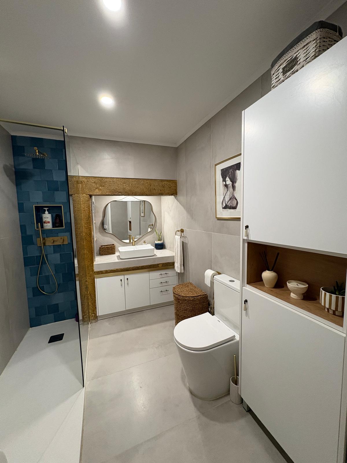 Casa de banho remodelada, com revestimento azul e detalhes dourados